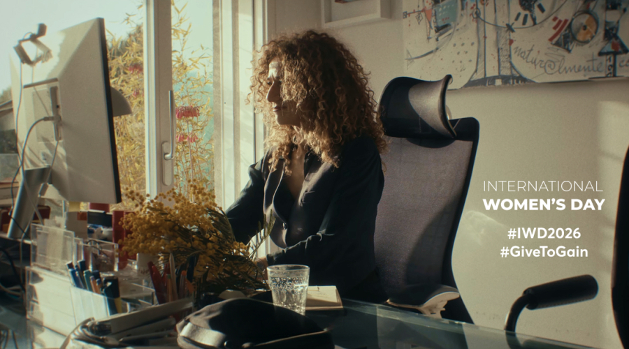 international women's day banner, woman CEO of company sitting at a desk working in low light, warm tones. 